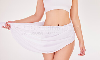 Buy stock photo Studio shot of an unrecognizable young woman posing in her underwear while wrapped in a sheet against a grey background