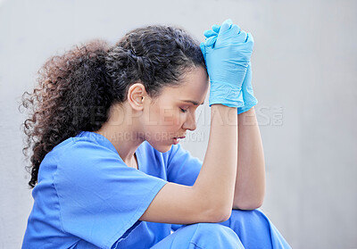 Buy stock photo Shot of a young female doctor looking sad against a city background