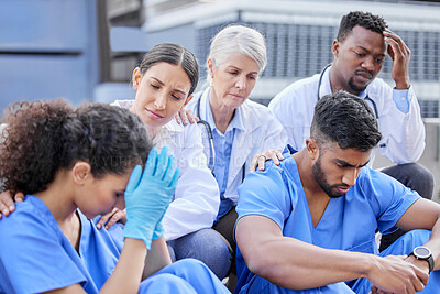 Buy stock photo Shot of a group of doctors looking sad against a city background