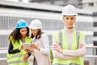 Buy stock photo Cropped portrait of an attractive mature female engineer standing with her arms folded with her colleagues in the background on a construction site