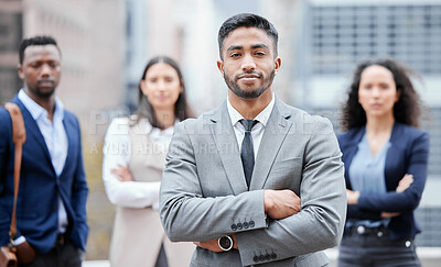 Buy stock photo Portrait of a confident young businessman standing with his arms crossed in the city with his colleagues in the background