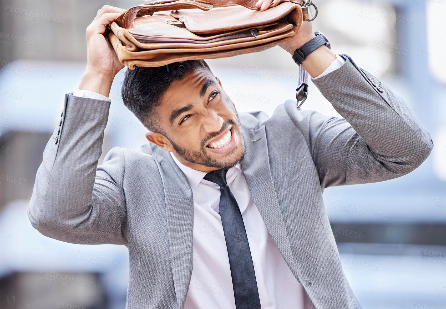 Buy stock photo Shot of a young businessman covering his head with a bag on a rainy day in the city