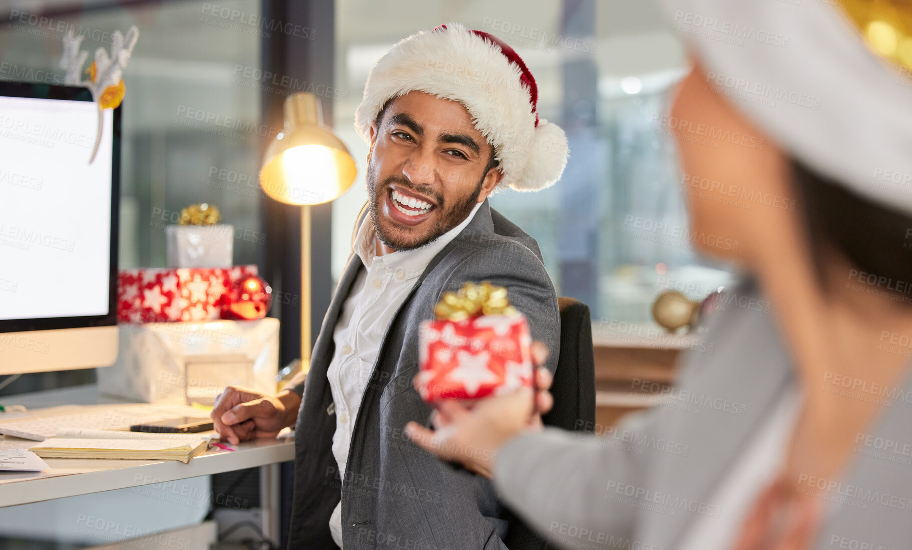 Buy stock photo Shot of a young businessman and businesswoman exchanging Christmas gifts in a modern office