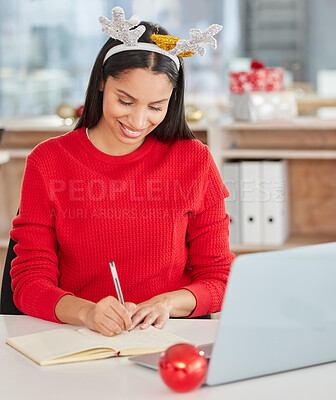 Buy stock photo Shot of a young businesswoman using a laptop and making notes in a modern office at Christmas
