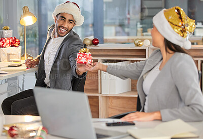 Buy stock photo Shot of a young businessman and businesswoman exchanging Christmas gifts in a modern office