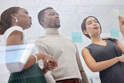 Buy stock photo Low angle shot of a group of businesspeople brainstorming with notes on a glass screen in an office