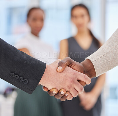 Buy stock photo Closeup shot of two unrecognisable businessmen shaking hands in an office with their colleagues in the background