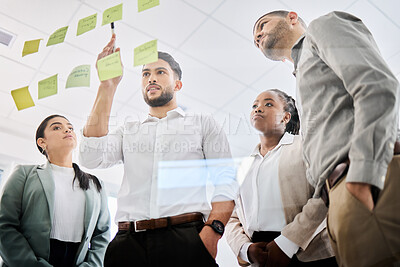 Buy stock photo Low angle shot of a group of businesspeople brainstorming together on a glass screen in an office
