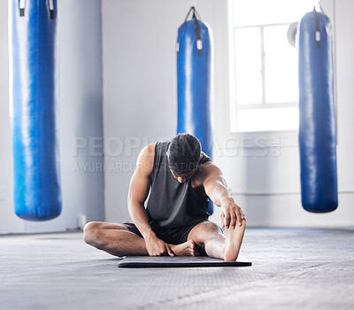 Buy stock photo Shot of a young man stretching his leg in the gym