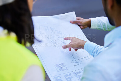 Buy stock photo Cropped shot of an unrecognisable group of architects standing together and looking at a blueprint
