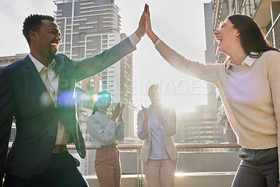 Buy stock photo Cropped shot of two young businesspeople high fiving on an office balcony while their colleagues applaud in the background