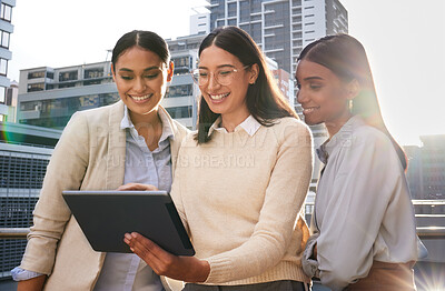 Buy stock photo Cropped shot of three attractive young businesswomen looking at a tablet while standing on an office balcony