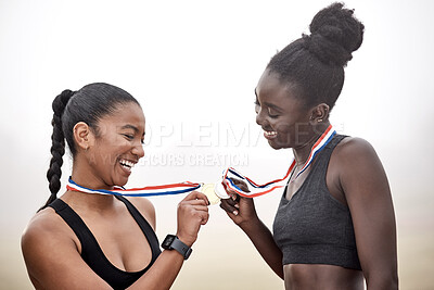 Buy stock photo Shot of two beautiful female athletes toasting their medals together