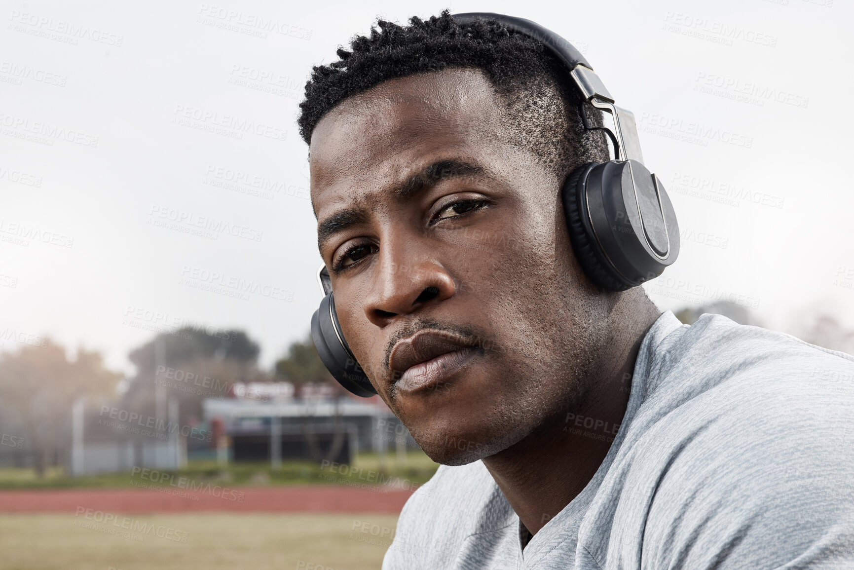 Buy stock photo Shot of a sporty young man wearing his headphones while out for a workout