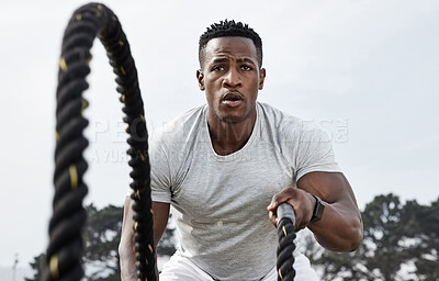 Buy stock photo Shot of an athletic young man doing heavy rope training outside