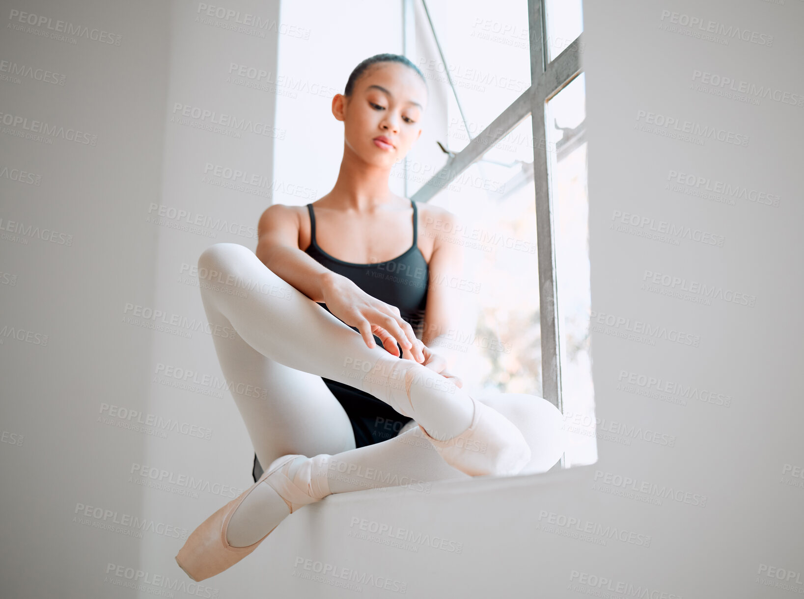 Buy stock photo Shot of a female ballerina sitting on a window sill