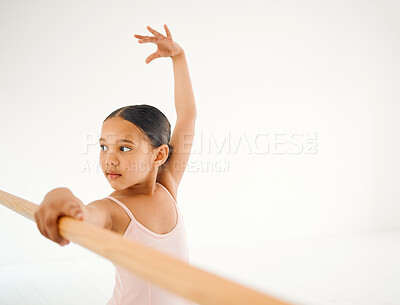Buy stock photo Shot of a little girl practicing ballet at a barre in a dance studio
