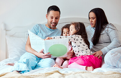 Buy stock photo Shot of a man holding a storybook while sitting with his wife and two daughters