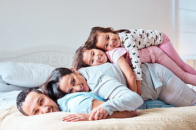 Buy stock photo Shot of a young family lying on top of each other on a bed