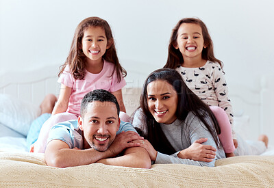 Buy stock photo Shot of a couple lying on bed with their two daughters