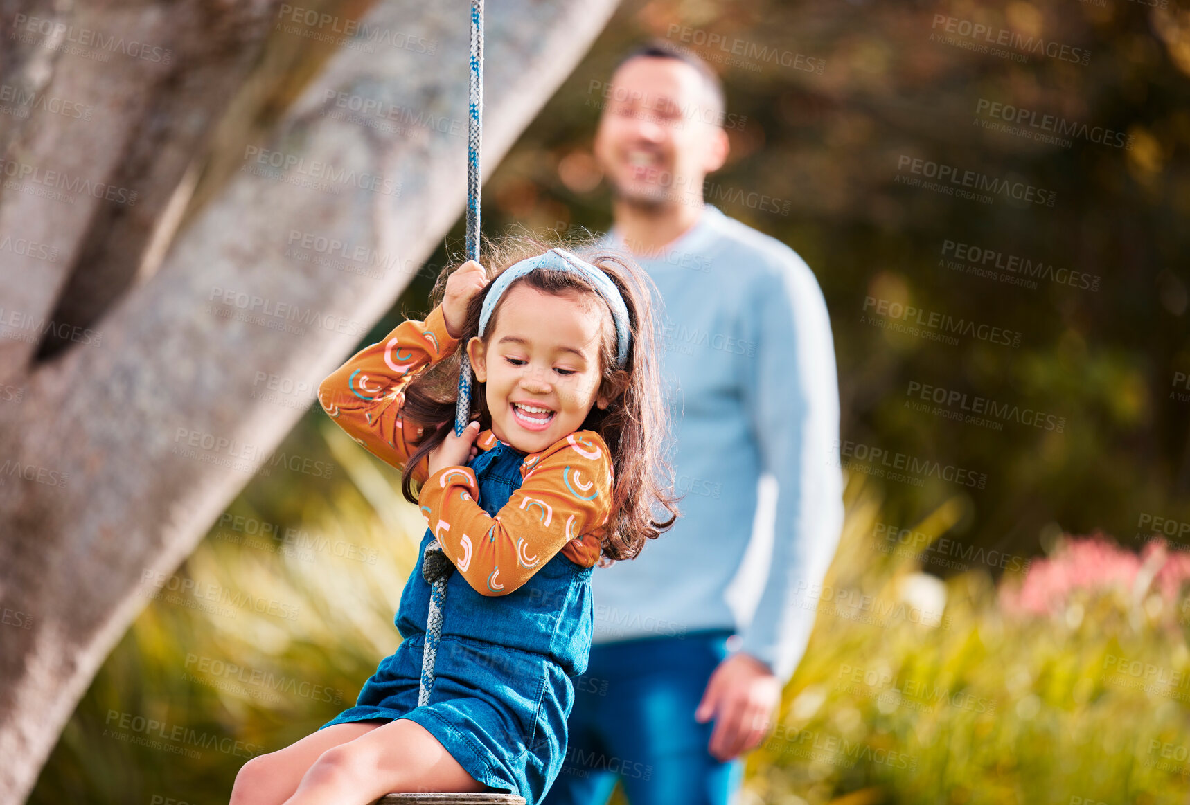 Buy stock photo Nature, swinging and fun of girl, smile and dad in playground, bokeh and child in park for games. Outdoor, freedom and playing in backyard, wellness and happy with rope on tree, healthy and kid