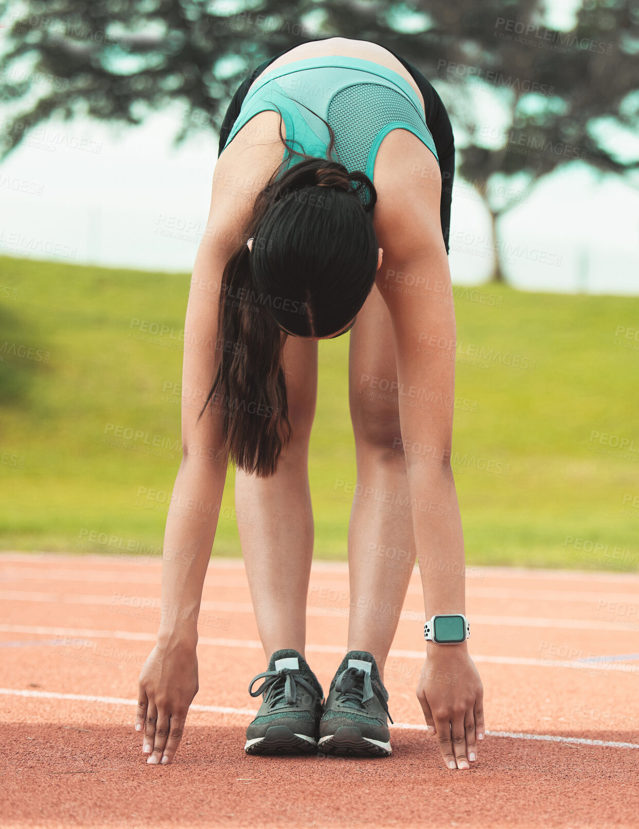 Buy stock photo Full length shot of an unrecognizable young sportswoman stretching on a running track