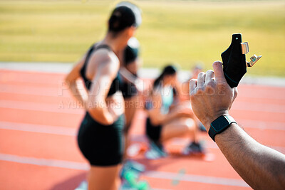 Buy stock photo Rearview shot of an unrecognizable man holding a starting gun while a group of sportswomen take up their positions on track