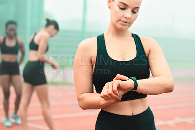 Buy stock photo Cropped shot of an attractive young sportswoman checking her smartwatch while standing out on the track
