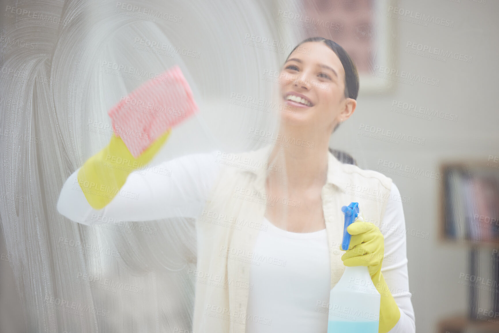 Buy stock photo Shot of a young woman cleaning a window in her home