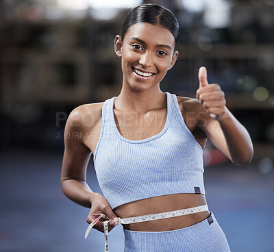 Buy stock photo Portrait of a sporty young woman showing thumbs up while measuring her waist in a gym