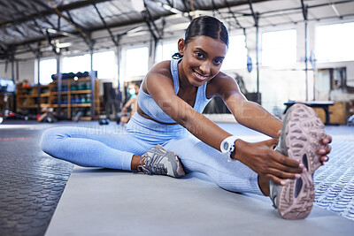 Buy stock photo Portrait of a sporty young woman stretching her legs while exercising in a gym