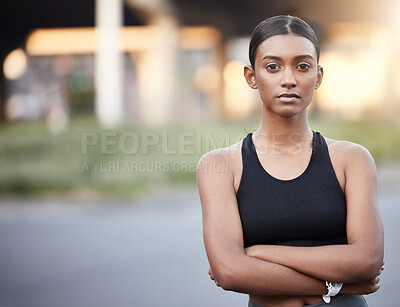 Buy stock photo Portrait of a sporty young woman standing with her arms crossed while exercising outdoors