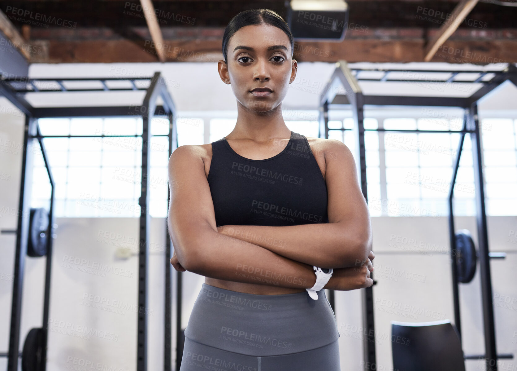 Buy stock photo Portrait of a sporty young woman standing with her arms crossed in a gym