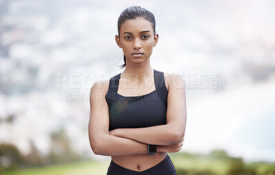 Buy stock photo Portrait of a sporty young woman standing with her arms crossed while exercising outdoors