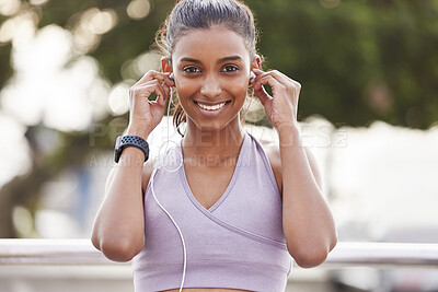 Buy stock photo Portrait of a sporty young woman wearing earphones while exercising outdoors