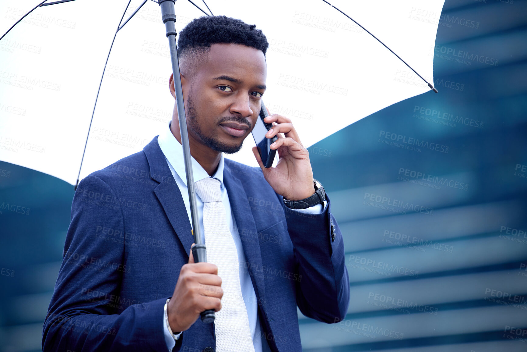 Buy stock photo Shot of a young businessman walking and using a phone in the city