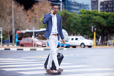 Buy stock photo Shot of a young businessman walking and using a phone in the city