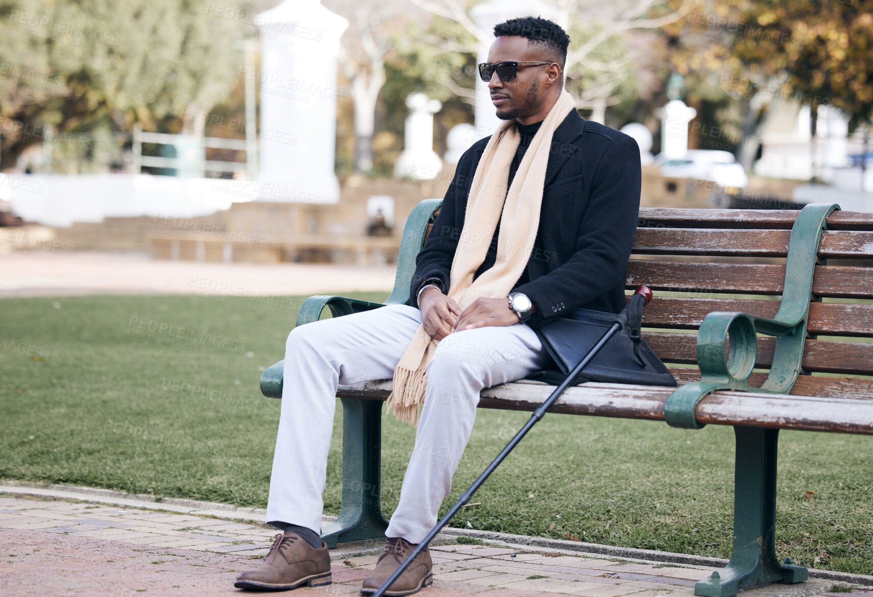 Buy stock photo Shot of a young man sitting on a bench in a park