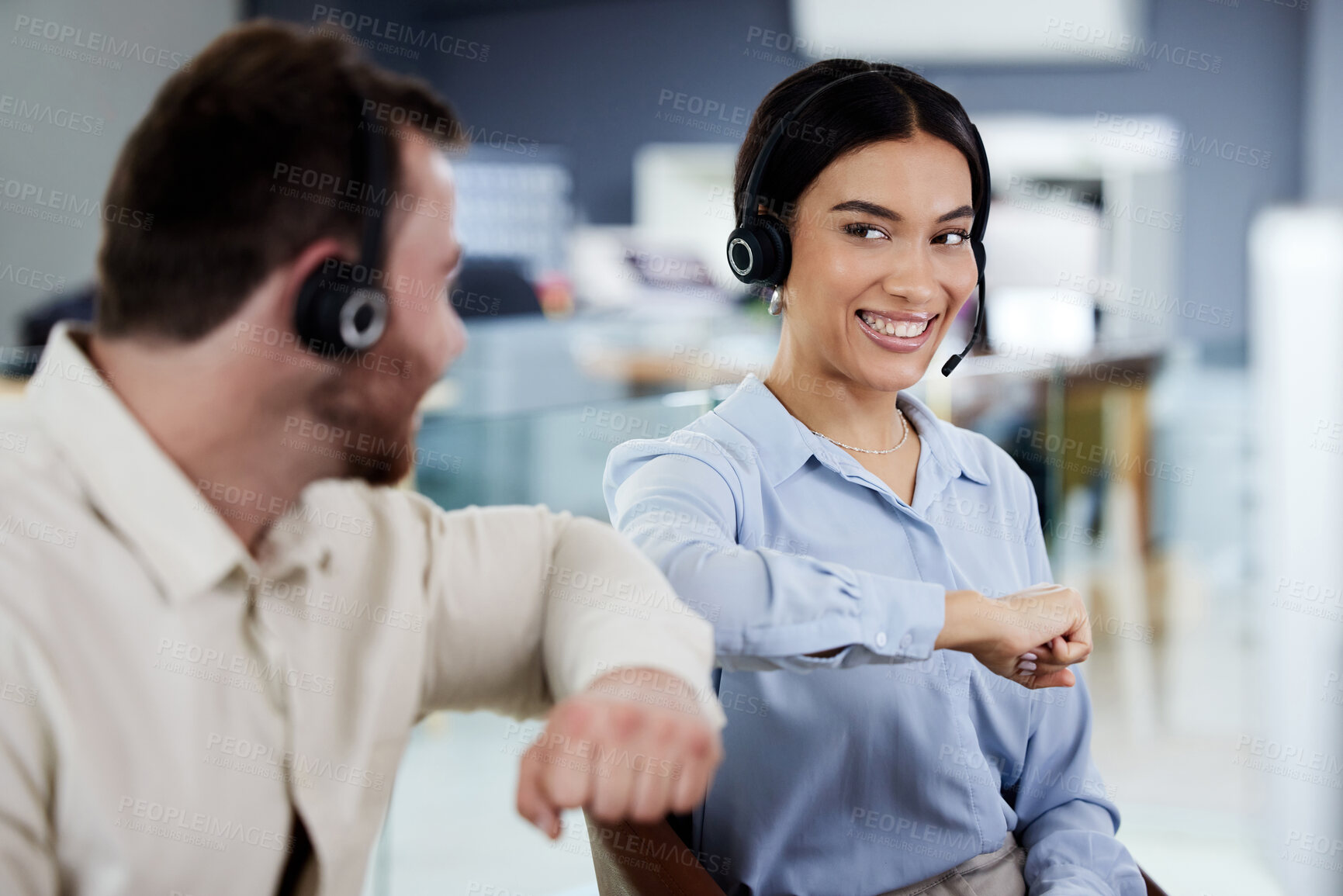 Buy stock photo Shot of a young call centre agent sitting with a colleague in the office and giving him an elbow bump
