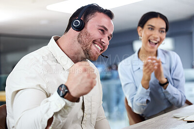 Buy stock photo Shot of a young call centre agent sitting in the office and celebrating a success while his colleague supports him