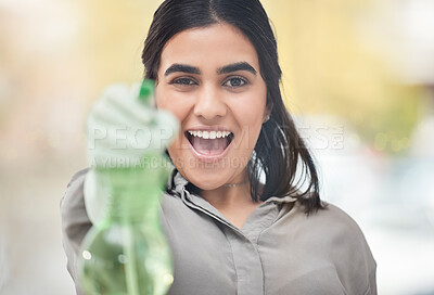 Buy stock photo Shot of a young woman holding a spray bottle while cleaning at home