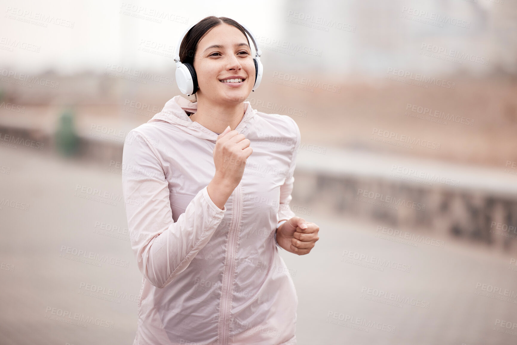 Buy stock photo Shot of a young woman using headphones during her run on the promenade