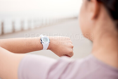 Buy stock photo Shot of an unrecognisable woman using a smart watch during her run on the promenade