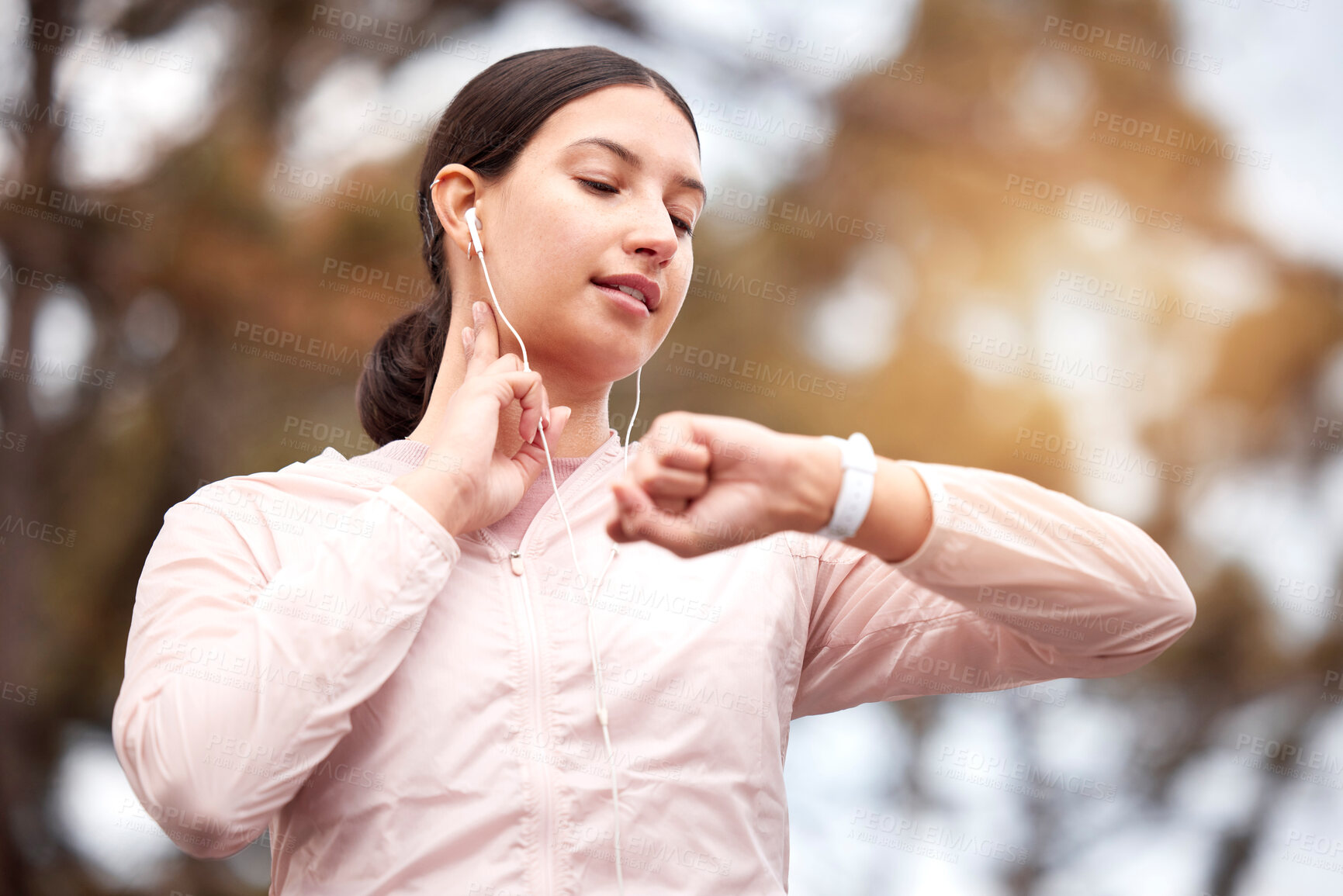 Buy stock photo Shot of a young woman checking her pulse while exercising in nature