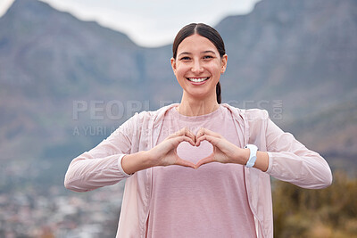 Buy stock photo Shot of a young woman making a heart shape with her hands while exercising outdoors