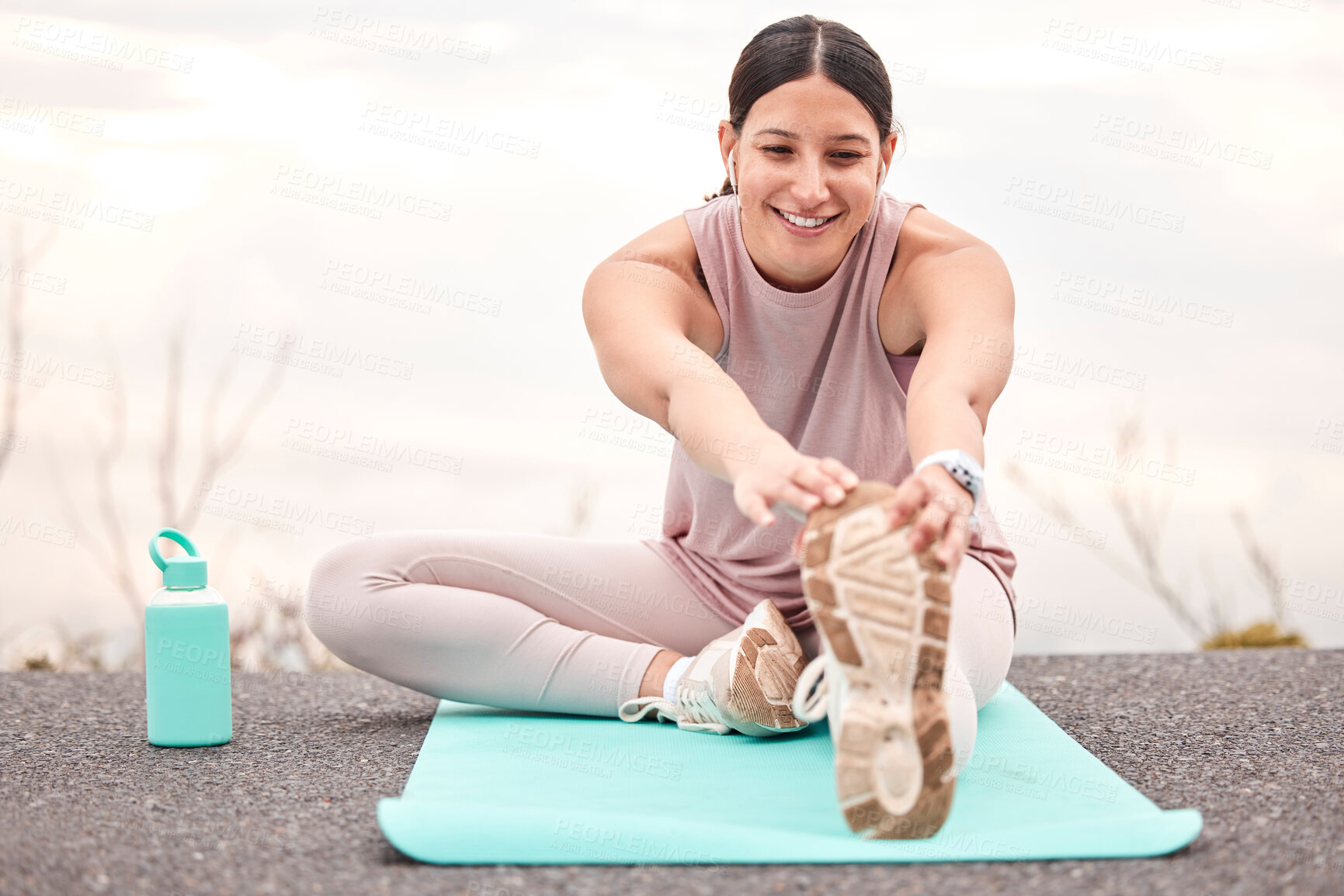 Buy stock photo Shot of a young female athlete stretching before a run in nature