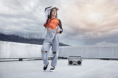 Buy stock photo Full length shot of an attractive young woman dancing on a rooftop against a stormy backdrop