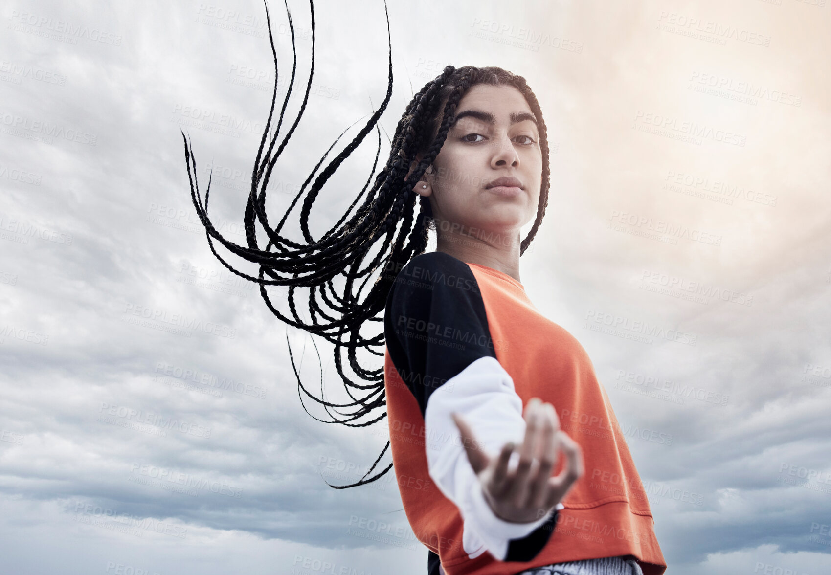 Buy stock photo Low angle portrait of an attractive young woman dancing against a stormy backdrop