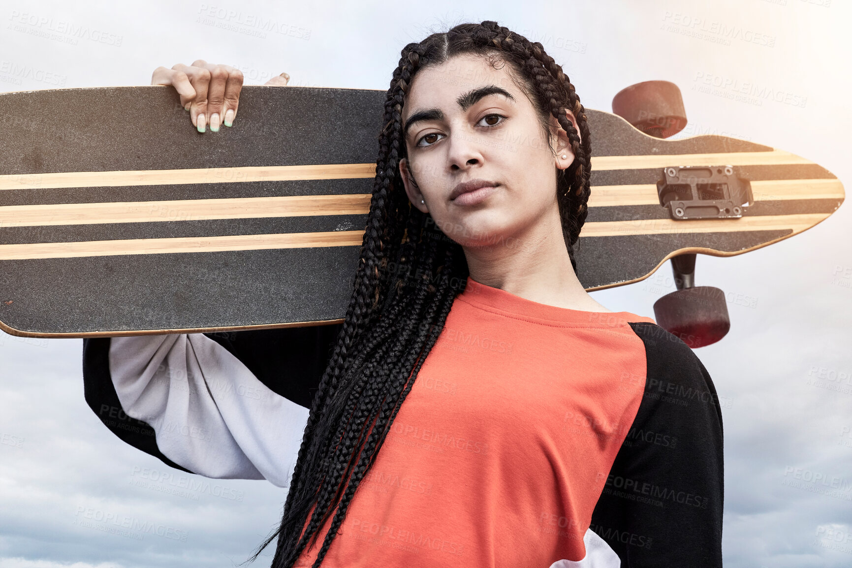 Buy stock photo Cropped portrait of an attractive young female skater standing with her longboard against a stormy backdrop