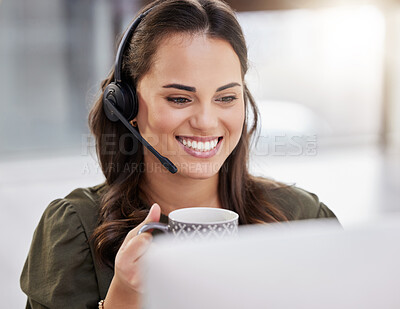 Buy stock photo Shot of a young call centre agent drinking coffee while working on a computer in an office